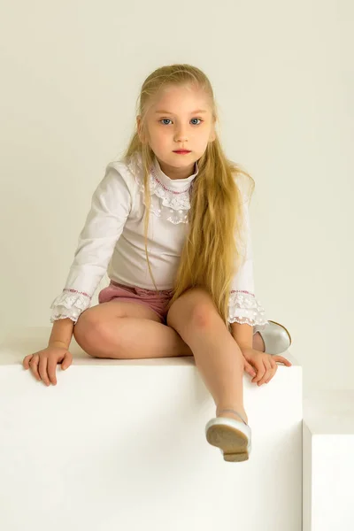 Niña posa para una revista en el estudio sobre un cubo blanco. —  Fotos de Stock