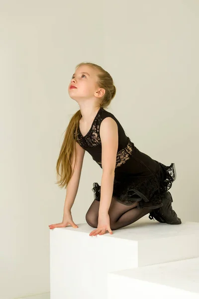 Petite fille en costume de danse posant en studio sur un cube blanc. — Photo