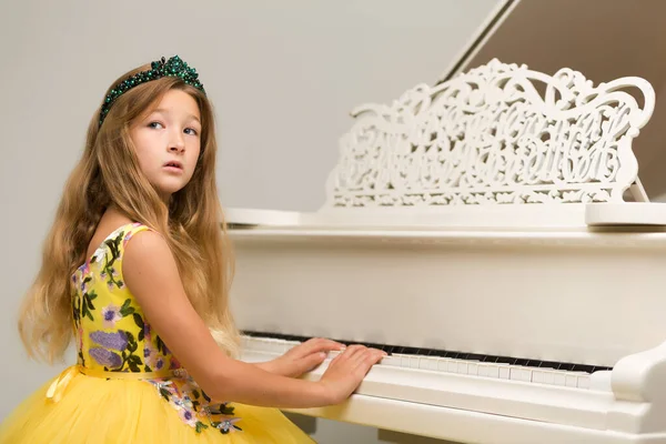 A menina está no piano de cauda branco. — Fotografia de Stock