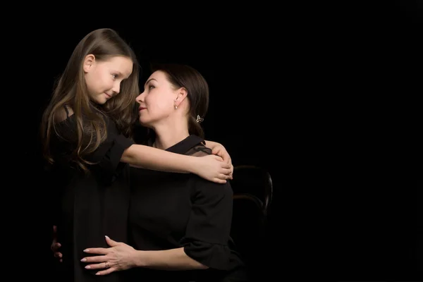 Mamá y su hija en el estudio sobre un fondo negro. —  Fotos de Stock