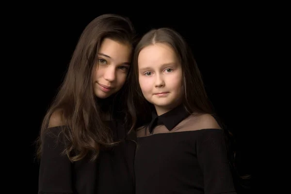 Дві маленькі дівчата позують в студії на чорному тлі. Стайт — стокове фото
