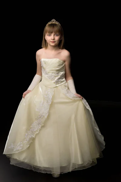 Uma menina em um vestido longo e elegante de uma princesa em um fundo preto. — Fotografia de Stock