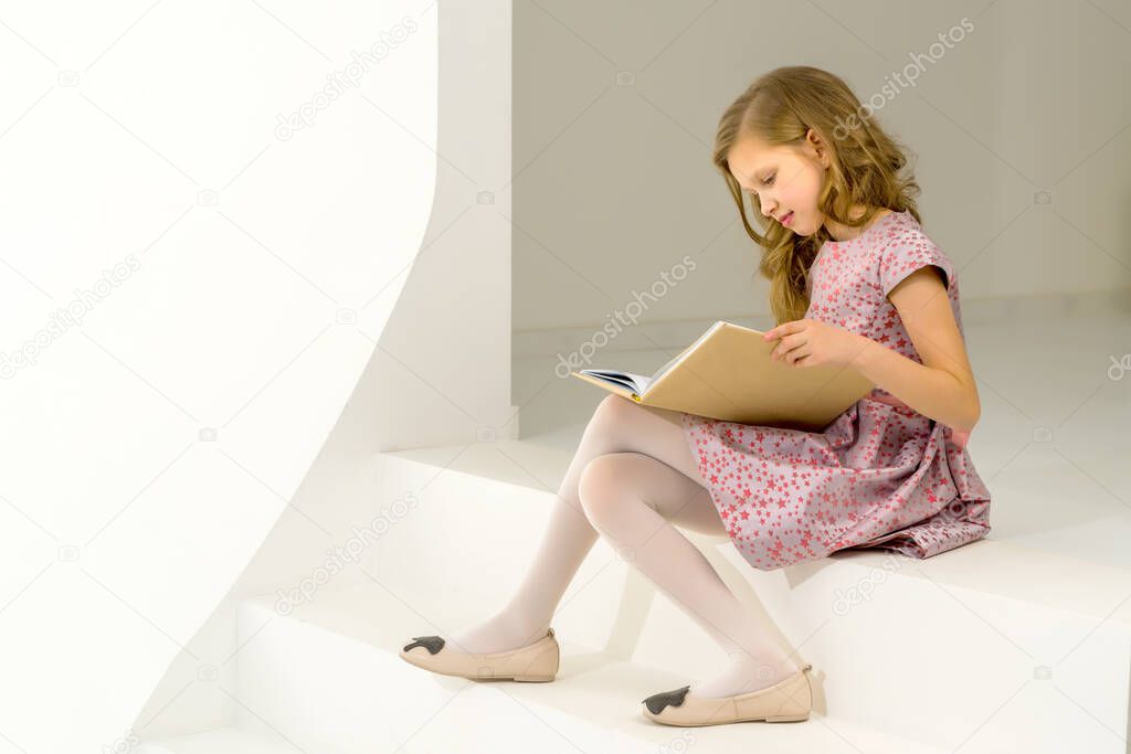 Beautiful Blonde Girl Sitting on Step and Reading Book with Int