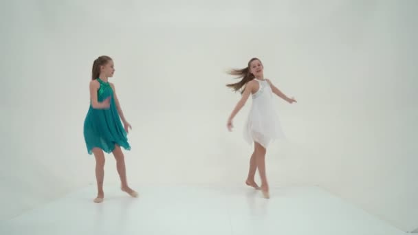 Irmãs gêmeas vestindo vestidos de esporte dançando contra o branco Backgro — Vídeo de Stock