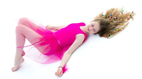 A cute girl gymnast of school age is lying on the floor with lon — Stock Photo, Image
