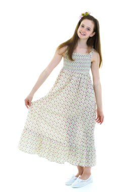 Güzel küçük bir kız rüzgârda duruyor, saçları ve kıyafetleriyle.