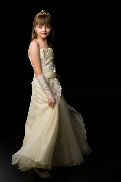 Uma menina em um vestido longo e elegante de uma princesa em um fundo preto. — Fotografia de Stock