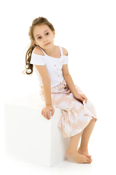 Ritratto di bella ragazza premurosa seduta sul cubo bianco — Foto Stock