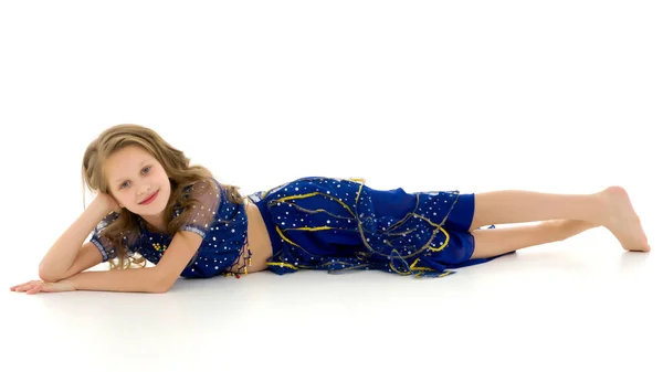 オリエンタルな衣装を着たリラックスした女の子が床に横たわり、カメラで微笑む — ストック写真
