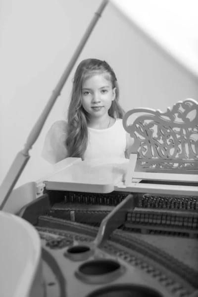 那女孩在白色的大钢琴旁. — 图库照片