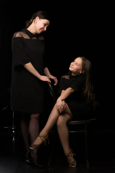 Maman et fille dans le studio sur un fond noir. — Photo