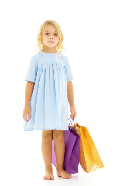 Ellerinde renkli çantaları olan küçük bir kız.. — Stok fotoğraf