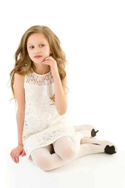 Menina bonita no elegante vestido de renda de marfim sentado no cubo branco — Fotografia de Stock