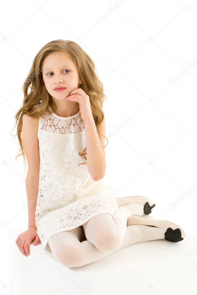 Beautiful Girl in Elegant Ivory Lace Dress Sitting on White Cube