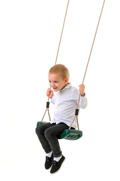 Mignon blond garçon balançant sur corde balançoire et regarder caméra — Photo