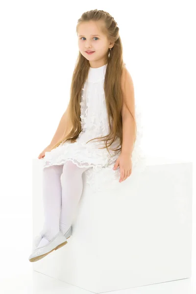 Little girl poses for a magazine in the studio on a white cube. — Stock Photo, Image