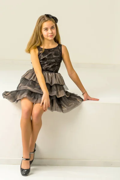 Το χαριτωμένο κοριτσάκι κάθεται στο στούντιο στις άσπρες σκάλες. στυλ και μόδα έννοια, ευτυχισμένη παιδική ηλικία. — Φωτογραφία Αρχείου