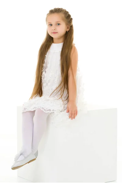Klein meisje poseert voor een tijdschrift in de studio op een witte kubus. — Stockfoto