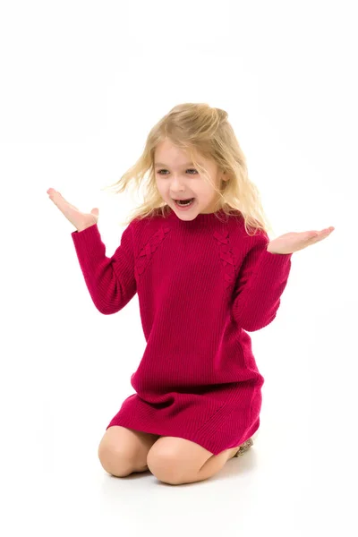 Roztomilé překvapené dívka na sobě červené šaty sedí na kolenou — Stock fotografie