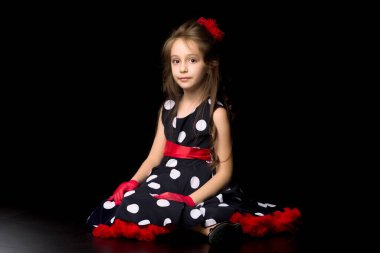 Siyah arka planda oturan eski moda elbiseli bir kız..