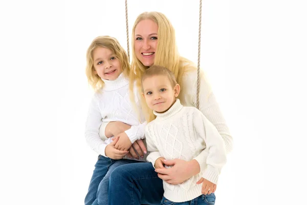 Glückliche Familie aus Mutter und zwei Kindern, die zusammen auf der Schaukel sitzen — Stockfoto