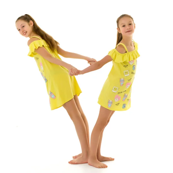 Sonriente adolescente niñas de pie espalda con espalda sosteniendo las manos —  Fotos de Stock