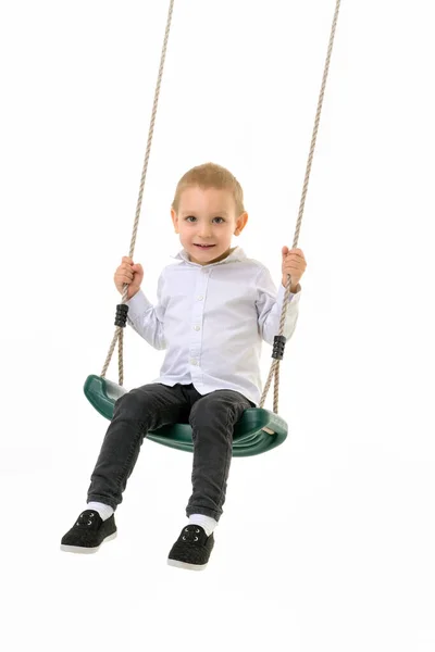 Bonito loiro menino balançando no corda balanço e olhando para câmara — Fotografia de Stock