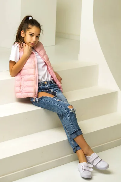 Küçük şirin kız stüdyoda beyaz merdivenlerde oturuyor. stil ve moda konsepti, mutlu çocukluk. — Stok fotoğraf