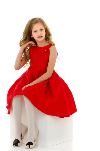 Portré a szép lány a stílusos piros ruha ül a fehér kölyök. — Stock Fotó