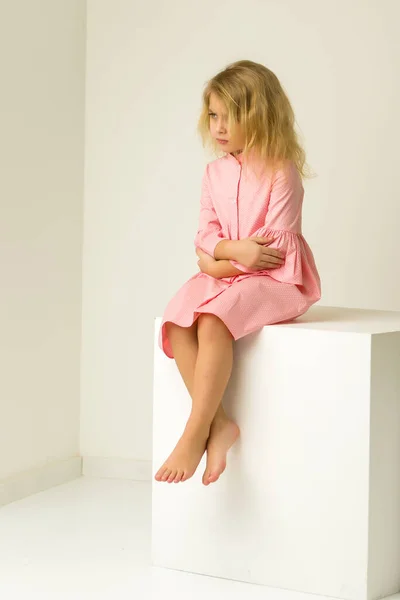 Sorgsen trött liten flicka sitter på golvet med vikta händer. — Stockfoto