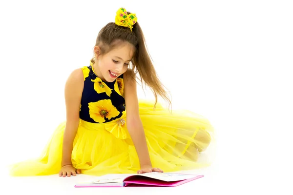 A schoolgirl girl is sitting on the floor surrounded by books. — Stock Photo, Image