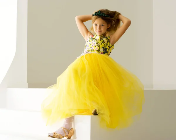 Menina bonito está sentado no estúdio nas escadas brancas. estilo e conceito de moda, infância feliz. — Fotografia de Stock