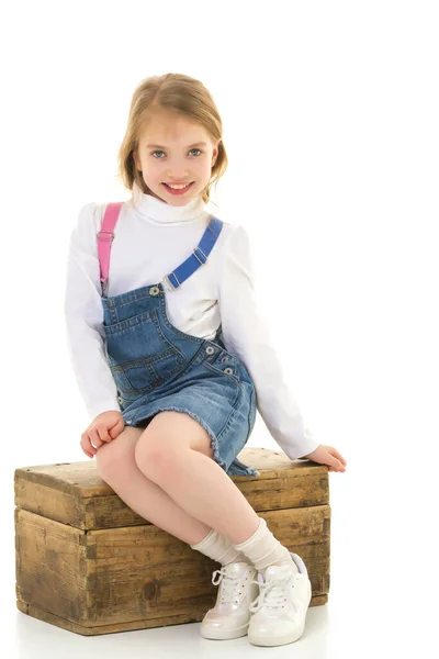 Mała dziewczynka siedzi na drewnianym pudełku.. — Zdjęcie stockowe