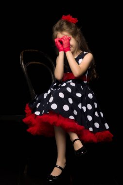 Siyah arka planda puantiyeli güzel bir kız oturuyor..