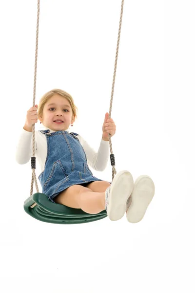 Linda menina loira balançando na corda balanço e olhando para a câmera — Fotografia de Stock