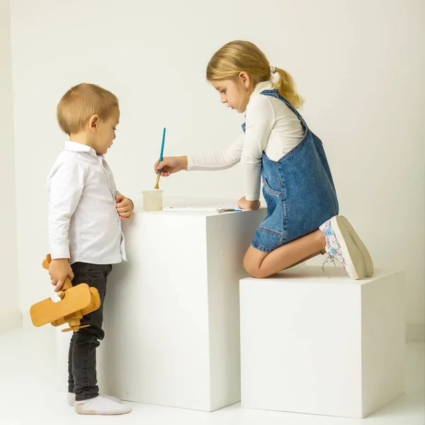 Cute Girl Sitting on Her Knees and Painting, Brother Looking at Her. — Stock Photo, Image