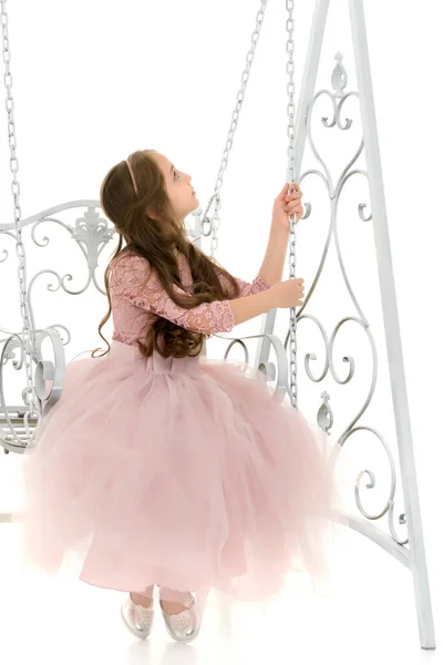 Okouzlující dlouhé vlasy dívka v pěkné šaty houpání na elegantní houpačka. — Stock fotografie