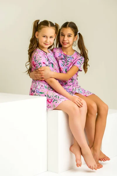 Duas meninas posando no estúdio em cubos brancos — Fotografia de Stock