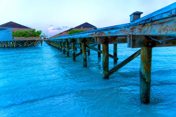 Drewniane mosty prowadzące do chatek nad brzegiem tropikalnego, ciepłego morza. Malediwy. Koncepcja turystyki. — Zdjęcie stockowe