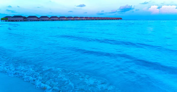 Puentes de madera que conducen a las cabañas a orillas del mar tropical y cálido. Maldivas. Concepto turístico. —  Fotos de Stock