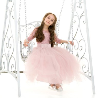 Yakışıklı, uzun saçlı, güzel elbiseli kız zarif salıncakta sallanıyor..