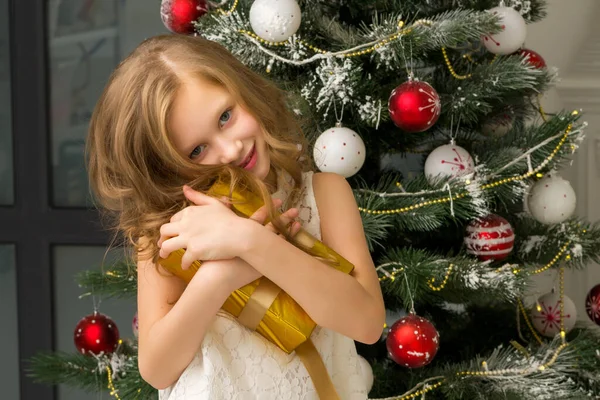 Tiener meisje in mooie witte jurk poseren in kerstmis interieur. — Stockfoto