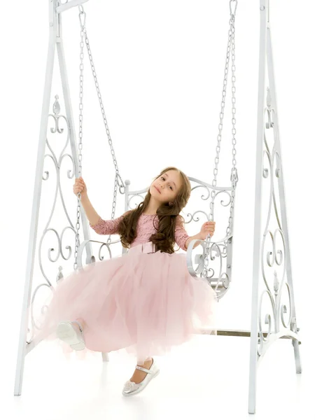 Encantadora menina de cabelos compridos em bom vestido balançando no balanço elegante. — Fotografia de Stock