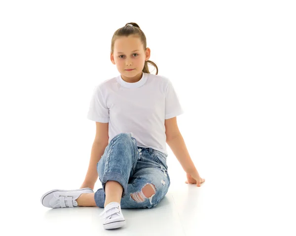 Malá holčička sedí na podlaze v čistém bílém tričku. — Stock fotografie
