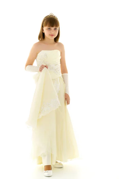 Een klein meisje in een lange, elegante jurk van een prinses. — Stockfoto