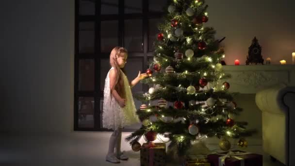 La niña decora un árbol de Navidad. Concepto de Año Nuevo, vacaciones familiares. — Vídeo de stock