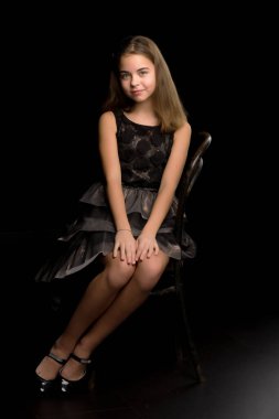 Eski bir Viyana sandalyesinde oturan küçük bir kızın portresi, siyah arka plan..