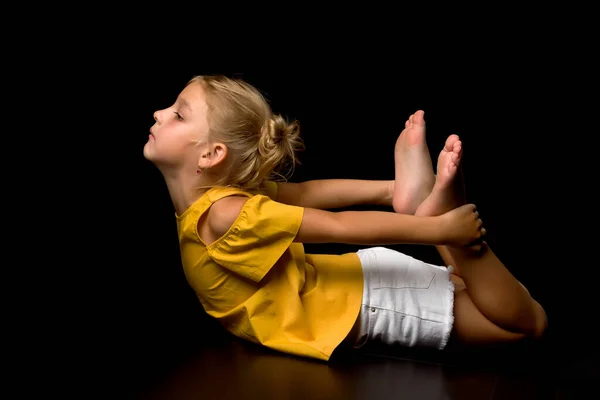 Carina bambina sdraiata sul pavimento in studio su uno sfondo nero — Foto Stock