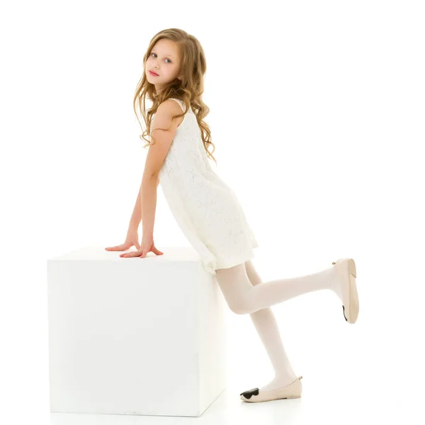 Bella ragazza in abito bianco in piedi e appoggiata sul cubo. — Foto Stock
