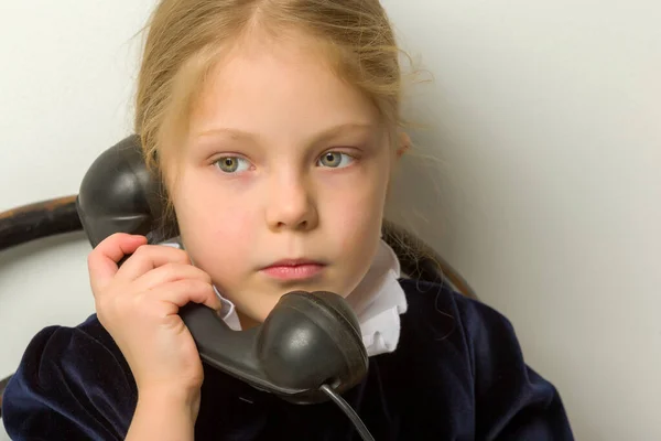 En liten flicka ringer i den gamla telefonen.. — Stockfoto